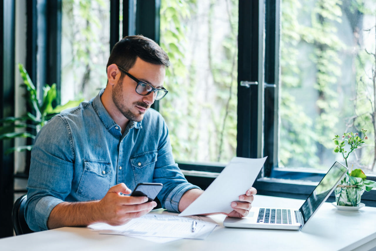 Man in glasses reviewing paperwork on start up costs