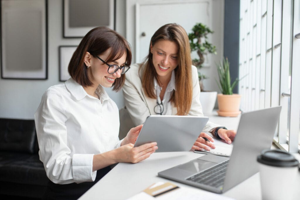 Two female colleagues looking at their business start up costs on a tablet together. 