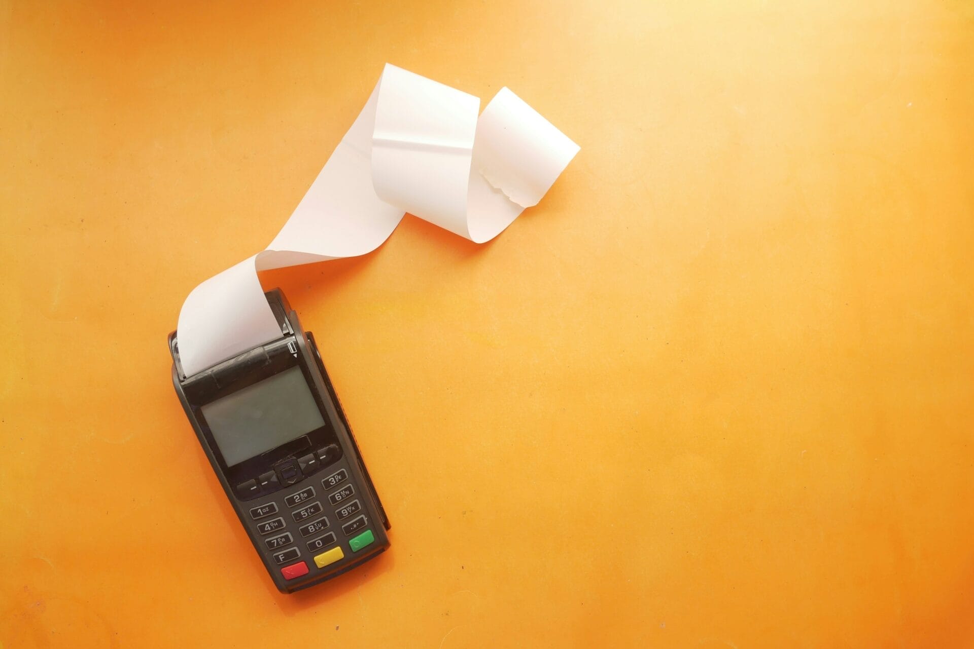 An accounting tool with a roll of paper coming out against an orange background.