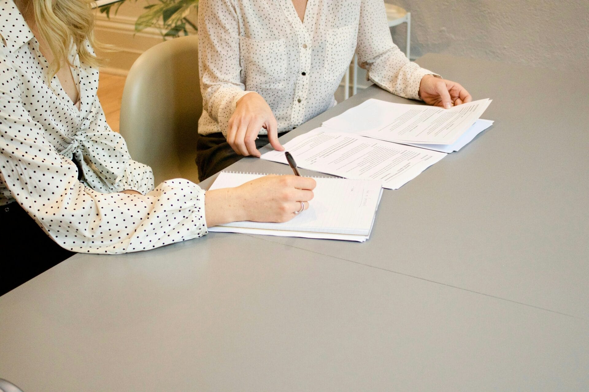 Two employees at a desk review paperwork together.